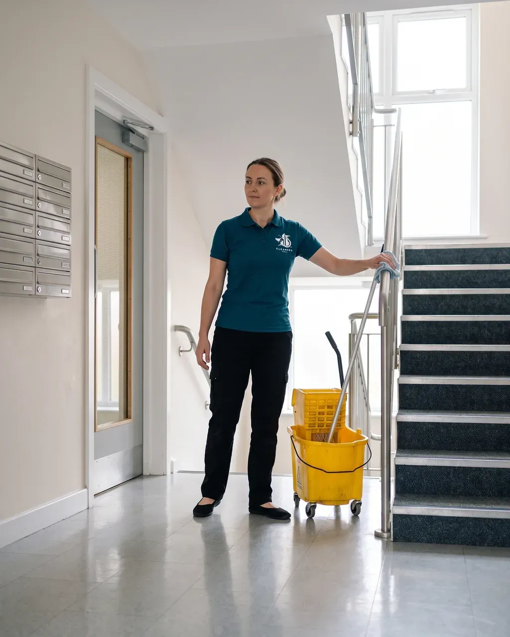 Cleaners Poole cleaner wiping down the handrail in the communal stairwell of a Poole block of flats
