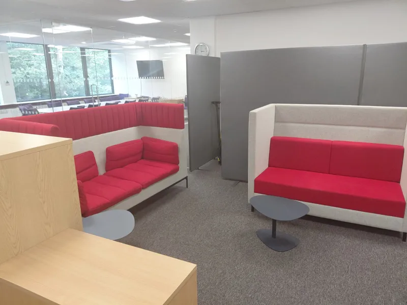 Red office breakout seating with small tables and grey carpet