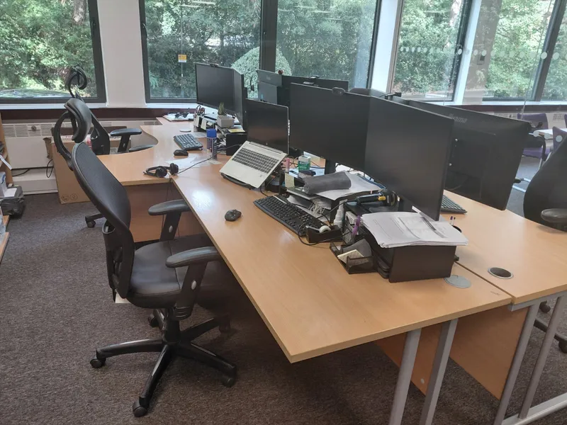 Office desks with monitors, chairs and carpet beside the windows